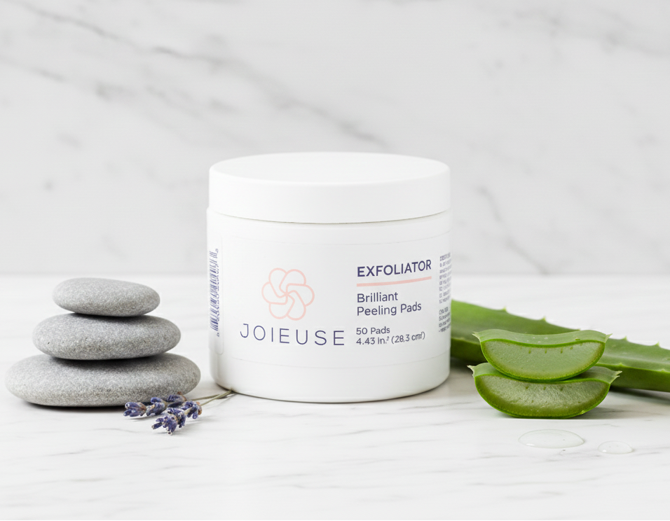 Joieuse exfoliator jar with peeling pads on a white surface with aloe vera and stones.